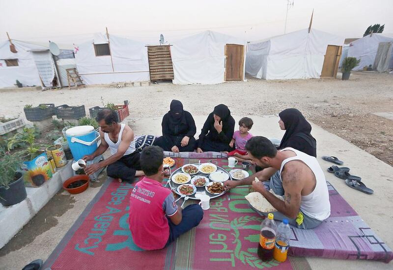 A family of Syrian refugees break their fasting outside their tent at a Syrian refugee camp in the  Bekaa Valley, Lebanon. Bilal Hussein / AP 