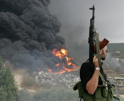 FILE PHOTO: A Lebanese Hezbollah guerrilla looks at a fire rising from a burning object in a Beirut suburb, Lebanon July 17, 2006. REUTERS/Issam Kobeisi/File Photo