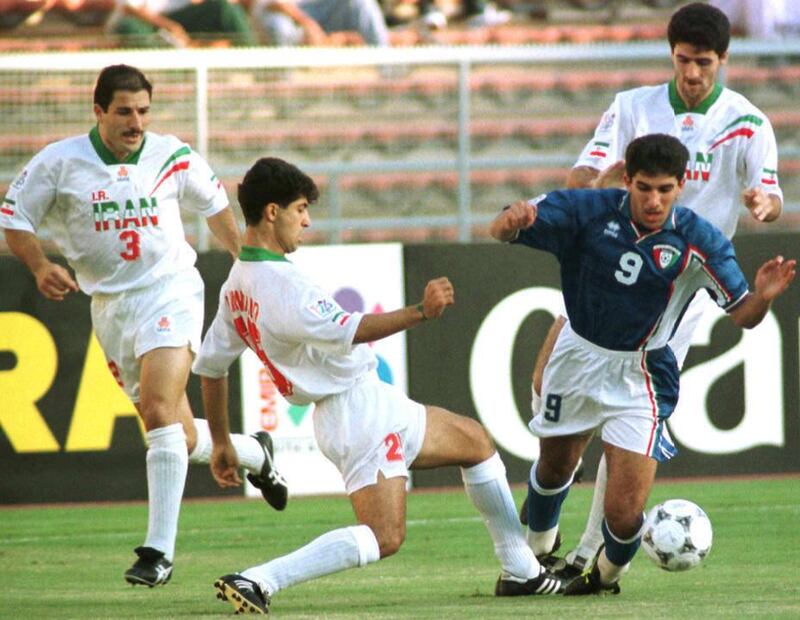 Iranian defender Mehrdad Minavan (C) tries to stop Kuwaity forward Bashar Abdul Aziz during their Asian cup finals in Abu Dhabi stadium 21 December. Iran beat Kuwait by penalty 4-3 and took third place in the Asian Cup finals. (Photo by RABIH MOGHRABI / AFP)