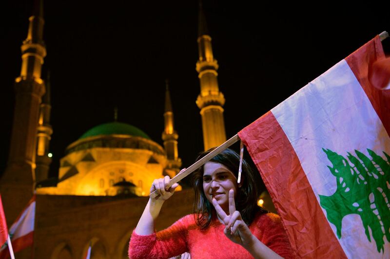 A protester flashes the victory sign as she carries a national flag during a rally at Martyrs Square in Beirut, Lebanon. EPA