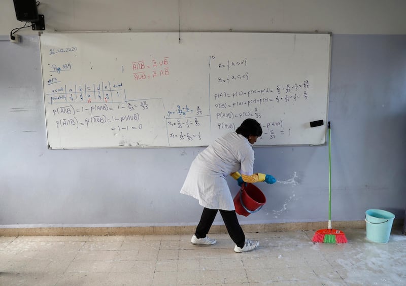 A worker splashes disinfectant in a classroom as part of sterilisation campaign against the new coronavirus, at the Evangelical School, in Loueizeh, east of Beirut, Lebanon. AP Photo