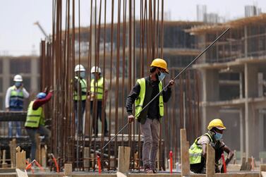 Workers wearing protective face masks stand on a building under construction in the New Administrative Capital (NAC), east of Cairo, amid concerns about the spread of the coronavirus disease (COVID-19), in Egypt May 6, 2020. Picture taken May 6, 2020. Reuters