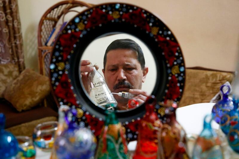 A Palestinian craftsman is reflected in a mirror as he decorates glass Christmas ornaments at a workshop in the southern West Bank city of Hebron. AFP