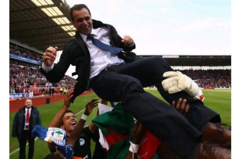 Wigan players throw manager Roberto Martinez in the air after avoiding the drop.