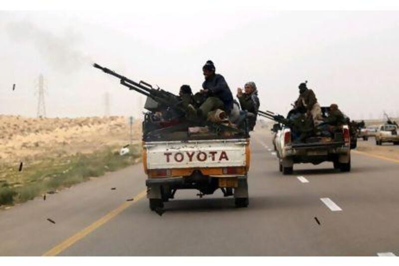 A rebel fighter fires his anti-aircraft gun as he flees together with other rebels from outside Ajdabiyah on the road to Benghazi.