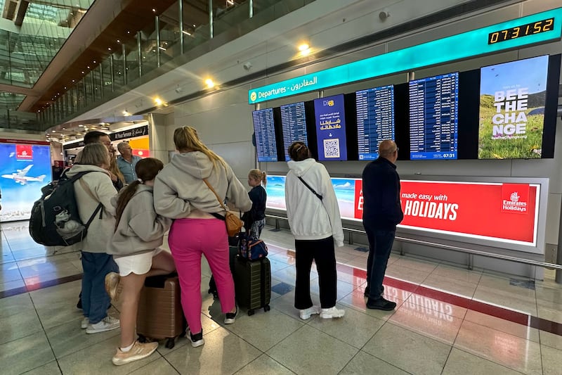 Passengers check flight information on screens at the Dubai International Airport. AFP