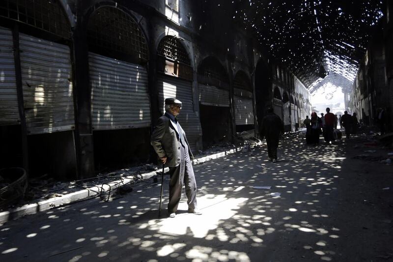 Rays of light shine through holes in the roof of the Maskuf covered market as Syrians stroll through the alleyways in the Old City of Homs, Syria.  Joseph Eid / AFP