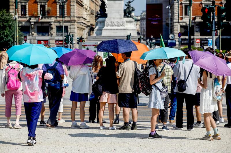 People use umbrellas to shield themselves from the sun in Milan, Italy. EPA 