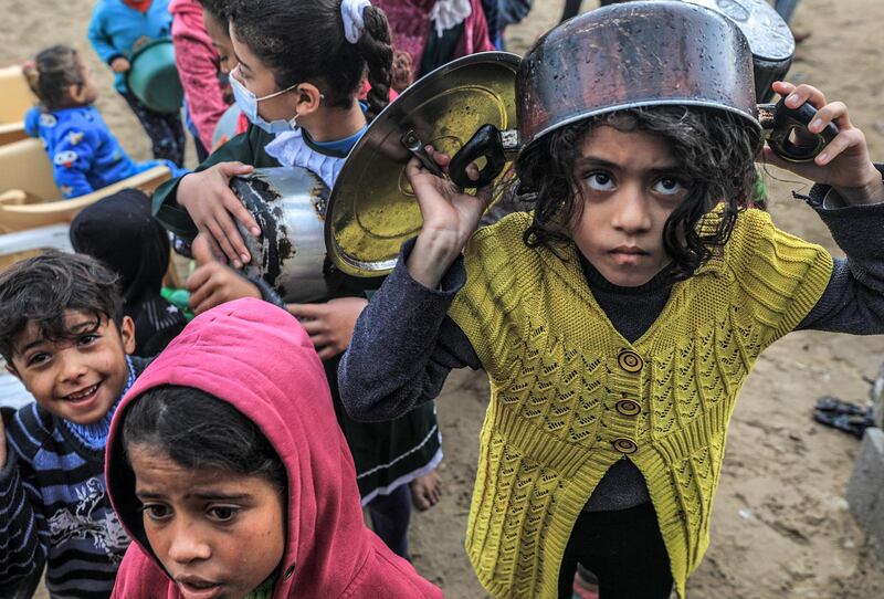 Palestinian children wait with pots to receive free food. EPA