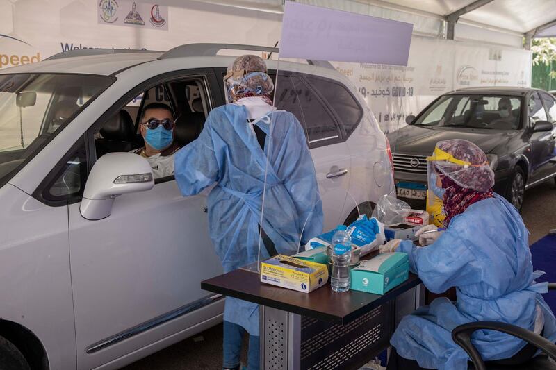 FILE - In this June 17, 2020 file photo, a health worker prepares to take swab samples to test for the coronavirus at a drive-through screening center in Cairo, Egypt. The coronavirus pandemic will exact a heavy toll on Arab countries, causing an economic contraction of 5.7% this year, pushing millions into poverty and compounding the suffering of those affected by armed conflict, a U.N. report said Thursday, July 23, 2020. The U.N.'s Economic and Social Commission for Western Asia expects some Arab economies to shrink by up to 13%, amounting to an overall loss for the region of $152 billion. (AP Photo/Nariman El-Mofty, File)