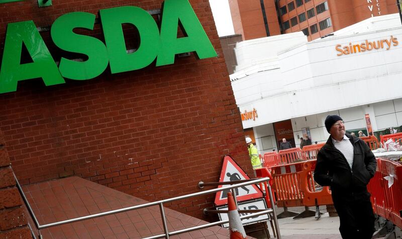 FILE PHOTO: A man walks past branches of ASDA and Sainsbury's in Stockport, Britain April 30, 2018. REUTERS/Phil Noble/File Photo