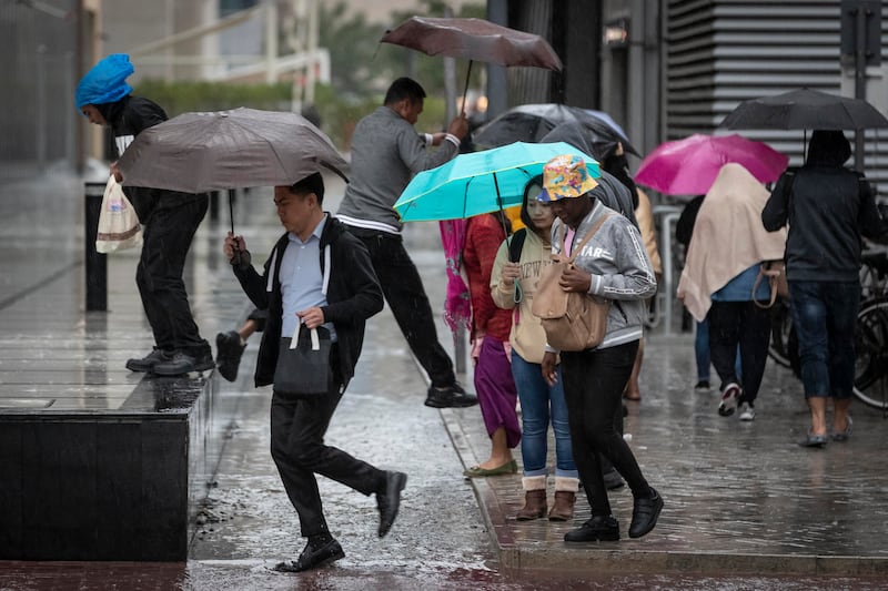 Pedestrians walk with umbrellas unfurled, navigating the rain-soaked streets in Barsha Heights. Antonie Robertson/The National