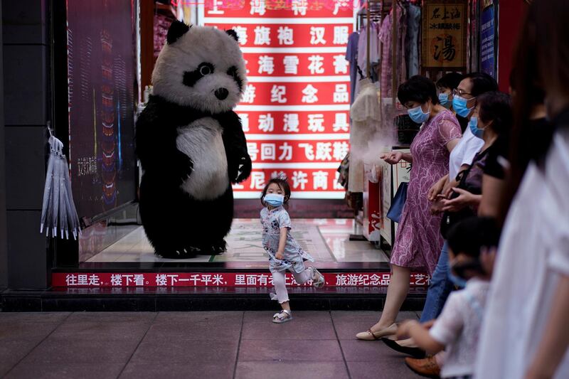 A girl wearing a face mask dances in front of a toy panda at a shopping area in Shanghai, following the Covid-19 outbreak, China. Reuters