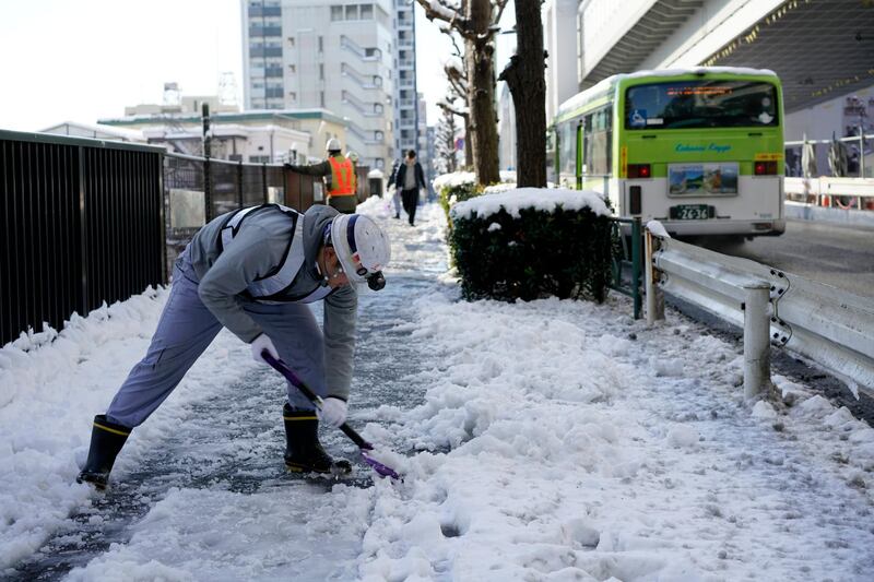 A worker clears snow from a sidewalk after snowfall in Tokyo on Tuesday. Franck Robichon / EPA
