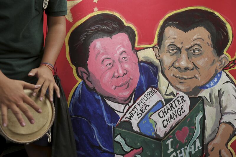 epa07178645 A placard with painting depicting Chinese President Xi Jinping and Philippine president Rodrigo Duterte during a protest near the Chinese Embassy upon the arrival of Chinese President Xi Jinping in Manila, Philippines, 20 November 2018. President Xi Jinping is in Manila for a two day state visit, during which he will attend a series of bilateral meetings and signing agreement ceremonies.  EPA/STR