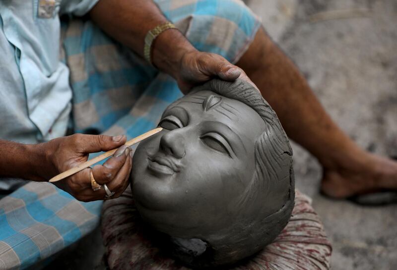 An Indian clay artist works on an unfinished face of Lord Shiva and Goddess Kali idols ahead of the Diwali festival at Kumartuly district in Kolkata, eastern India,18 October 2019. Kali, the Goddess of Power, is worshiped during the Hindu festival. EPA