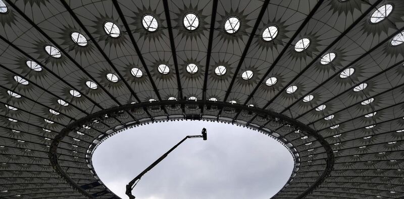 A worker stands on a hoist inside The NSC Olimpiyskiy Stadium in Kiev, on May 14, 2018, ahead of the 2018 UEFA Champions League Final football match between Liverpool and Real Madrid. Sergei Supinsky / AFP Photo