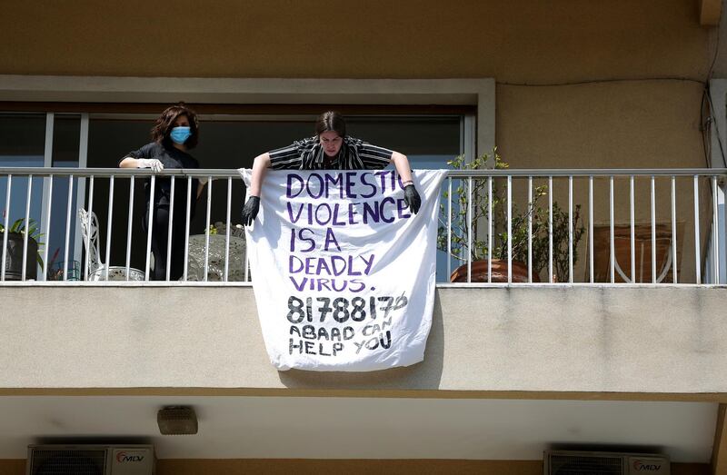 Lebanese woman hang a banner on their balcony in Beirut on April 16, 2020 during an awareness campaign by the Lebanese NGO ABAAD against domestic violence. in light of the current lockdown, many women in Lebanon who are victims of domestic violence found themselves stuck at home with their abusers. The number of abuse cases is on the rise. The campaign dubbed #LockdownNotLockup aims to raise awareness on the issue and most importantly help spread Abaad’s safety hotline. ABAAD is a resource centre for gender equality. (Photo by PATRICK BAZ / ABAAD)