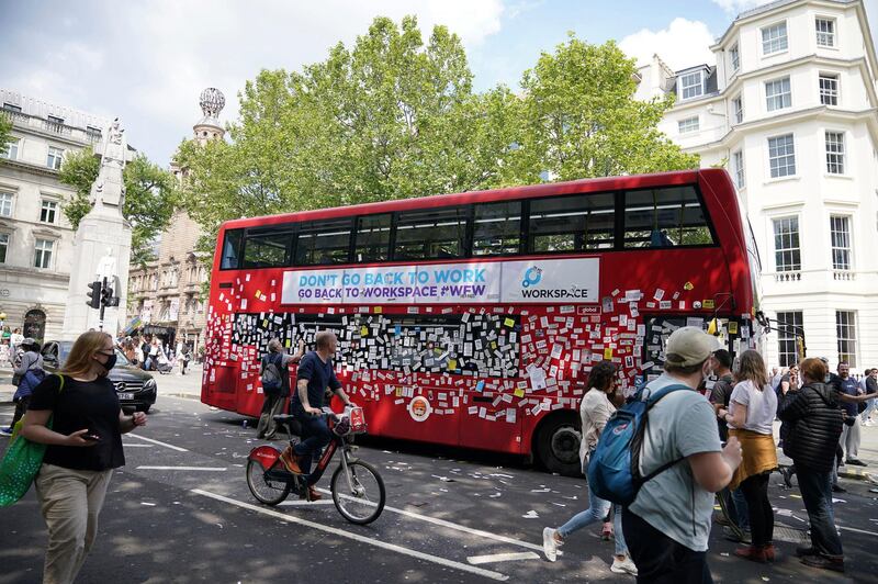 People view a bus covered in anti-vaccine stickers near Trafalgar Square in central London. AP Photo