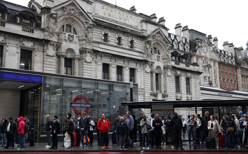 Commuters wait at a bus stop outside Victoria train station. AFP