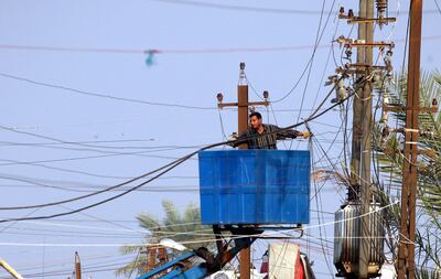 A maintenance worker repairs power lines, cut due to heavy rainfall, in the Iraqi capital Baghdad, on November 23, 2013. Flooding and heavy rain across Iraq has caused widespread structural damage across the country. AFP PHOTO/SABAH ARAR (Photo by SABAH ARAR / AFP)