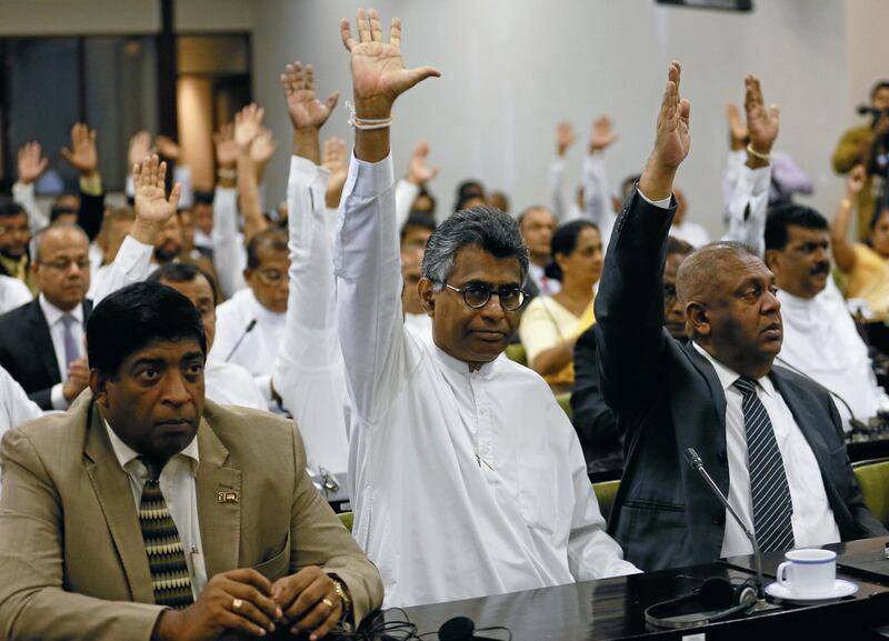 Lawmakers backing deposed Sri Lankan Prime Minister Ranil Wickremesinghe, raise hands during a meeting with Karu Jayasuriya. Reuters