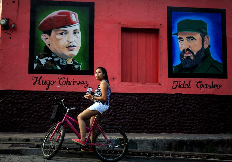 A woman sits on her bicycle in front of murals of Venezuela's late president Hugo Chavez and an image of Cuba's late president Fidel Castro in Altagracia, Nicaragua. /Oswaldo Rivas / Reuters