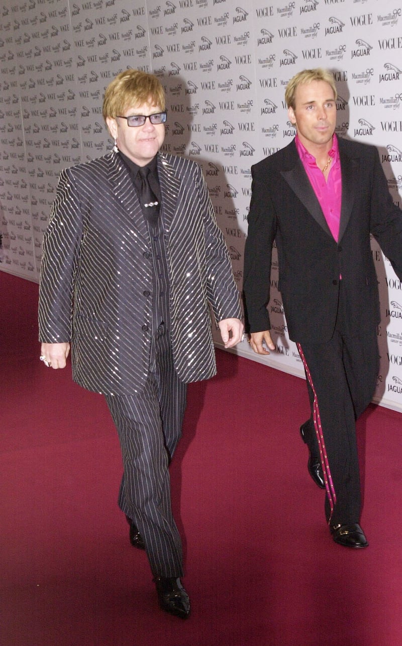 Elton John, in a sparkling pinstriped suit, and David Furnish arrive at Vogue's It's Fashion charity gala in Buckinghamshire, England on June 11, 2001. Getty Images