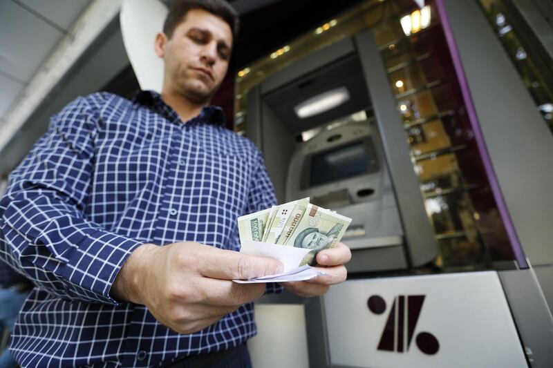 A man withdraws Iranial Rials from an automated teller machine in the capital Tehran on July 31, 2018.

Iran's currency traded at a fresh record-low of 119,000 to the dollar on today, a loss of nearly two-thirds of its value since the start of the year as US sanctions loom. / AFP PHOTO / ATTA KENARE