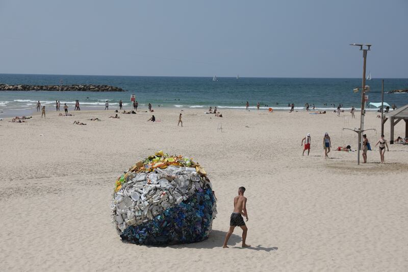 An art installation created by Tal Tenne Czaczkes of a large beach ball made of plastic waste, on display at Gordon beach in Tel Aviv, Israel. EPA