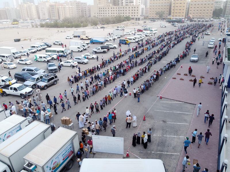 Fasting Muslim worshippers queue to receive iftar meals, donated by a charity, in Mahboula, south of Kuwait City. AFP