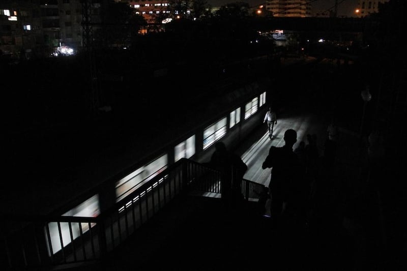People walk along the platform using light from the train at the Maadi metro station during an electricity outage.