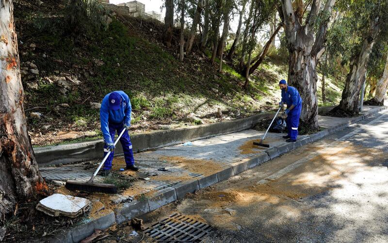 Workers clean up at the site of a car crash where prisoners who had fled a detention centre in a vehicle had died following their escape earlier, in Baabda.  AFP