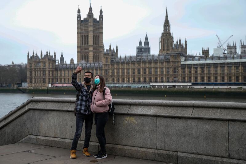 A couple, wearing protective face masks, takes a selfie in view of the Houses of Parliament in London, UK, on March 19, 2020. Bloomberg