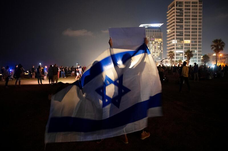 Protesters wave the Israeli national flag during a protest against Israel's Prime Minister Benjamin Netanyahu in Tel Aviv. AP