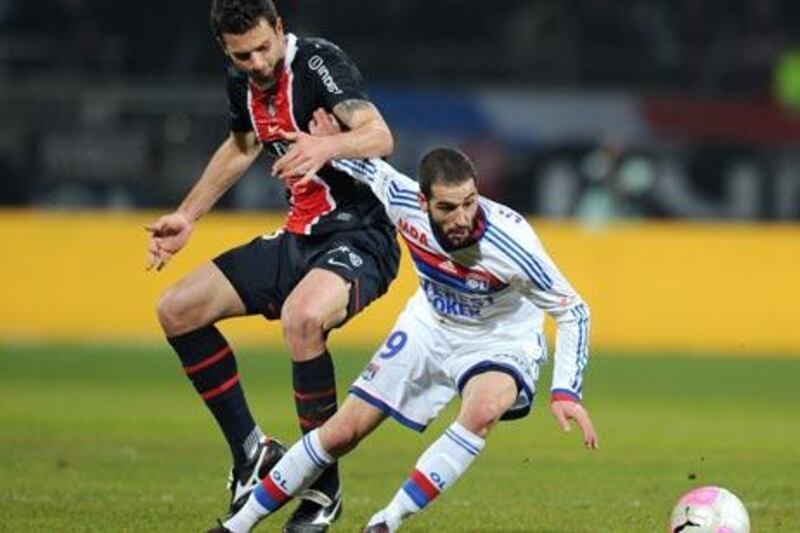 Lyon's forward Lisandro Lopez, right, fights for the ball with PSG' midfielder Thiago Motta.