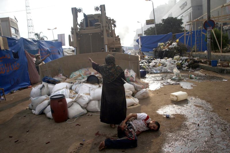 An Egyptian woman tries to stop a military bulldozer from hurting a wounded youth as Egyptian security forces moved in to disperse supporters of Egypt's deposed president Mohammed Morsi. Mohammed Abdel Moneim / AFP

