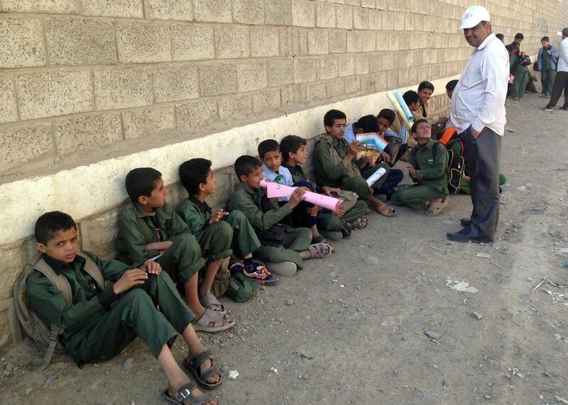 Yemeni children sit outside a school used by Houthi rebels. AFP 