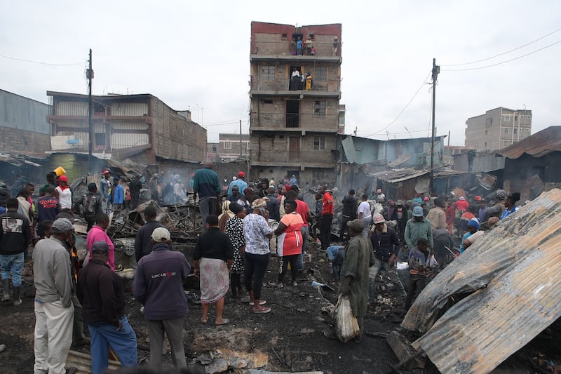 Residents stand on the rubble of iron-sheet houses destroyed by a fire caused by an electric fault, in Mathare, Nairobi. AFP