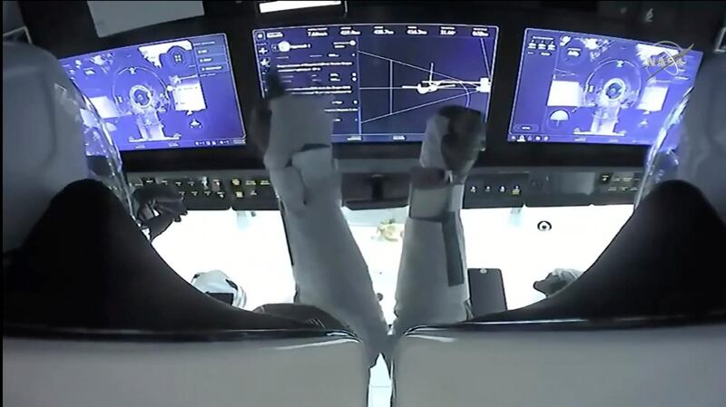 Astronauts Mike Hopkins, left, and Victor Glover monitor controls aboard SpaceX Dragon as the capsule approaches the International Space Station. Nasa TV / AP