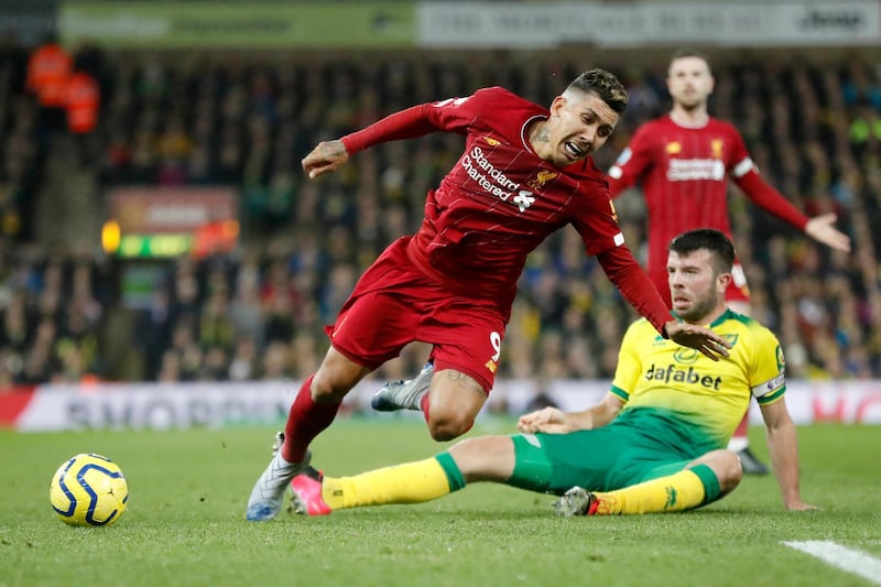 Liverpool's Roberto Firmino, center, duels for the ball with Norwich City's Grant Hanley during the English Premier League soccer match between Norwich City and Liverpool at Carrow Road Stadium in Norwich, England, Saturday, Feb. 15, 2020. (AP Photo/Frank Augstein)