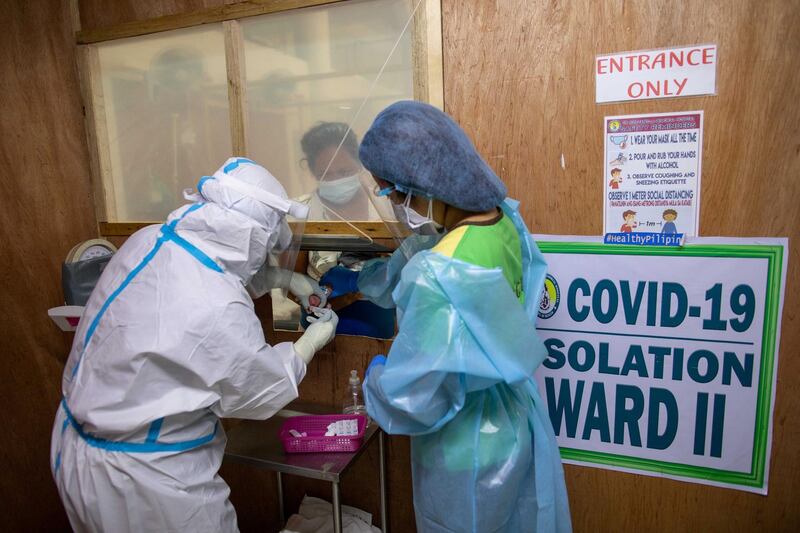 Health workers get a blood sample from a newborn through a makeshift window on the COVID-19 isolation area  in Manila, Philippines. REUTERS