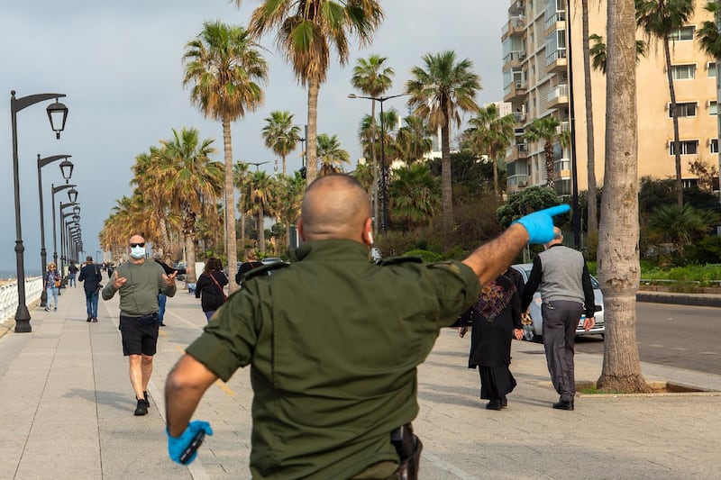 A municipal policeman orders people to evacuate the corniche, or waterfront promenade, along the Mediterranean Sea, as the country's top security council and the government were meeting over the spread of coronavirus, in Beirut, Lebanon. AP Photo