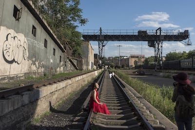 A woman poses for a photograph on railroad tracks in the 798 art district in Beijing, China, on Friday, June 24, 2016. Audi set up its China design center in Beijing's 798 art district, a sprawl of old military electronics facilities taken over in the early 2000s by the capital's booming contemporary art scene and now being invaded by design companies and entrepreneurs. Photographer: Gilles Sabrie/Bloomberg