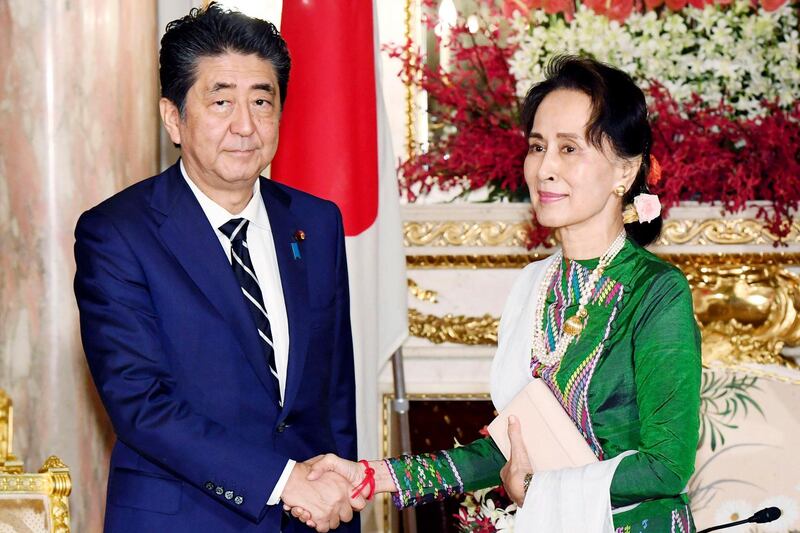 Japan's Prime Minister Shinzo Abe, left, shakes hands with Myanmar's leader Aung San Suu Kyi at the state guesthouse in Tokyo.  Suu Kyi is in Tokyo to attend a palace ceremony for the enthronement of Emperor Naruhito.  AP