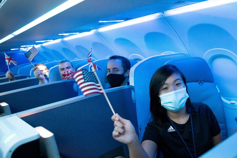 Passengers wear protective masks and hold American and British flags as their JetBlue flight to London takes off from JFK International Airport, New York. Reuters