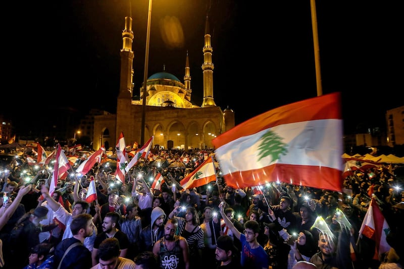 epaselect epa07947565 Lebanese protesters wave Lebanese flags and shout anti-government slogans during a protest in front Al-Ameen mosque in downtown Beirut, Lebanon, 24 October 2019. Protests entered their second week, with hundreds of thousands of Lebanese taking to the streets to protest proposals of tax hikes and state corruption, and calling for the overthrow of the entire political regime  EPA/NABIL MOUNZER