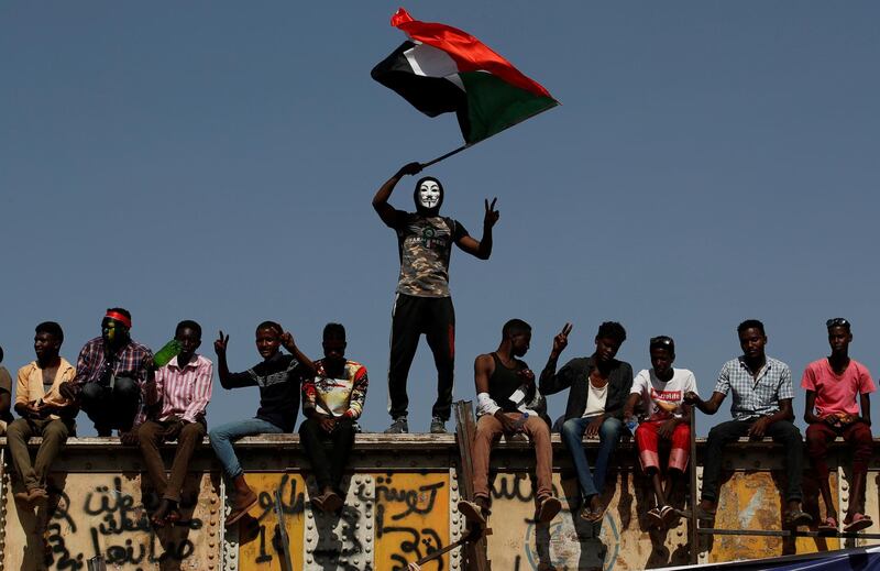 A Sudanese protester wearing a Guy Fawkes mask waves a national flag outside the defence ministry compound in Khartoum. Reuters