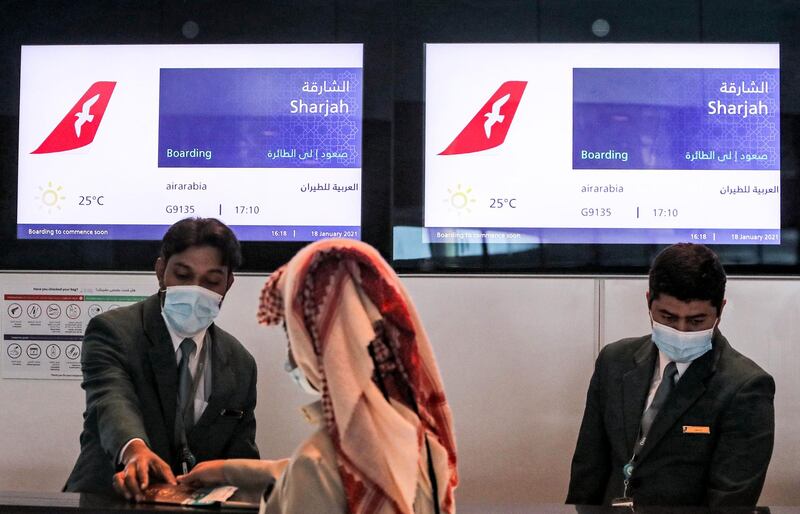 An Air Arabia check-in staff member assists a passenger at Doha's Hamad International Airport, before passengers board the first flight to Sharjah on January 18, 2021. AFP