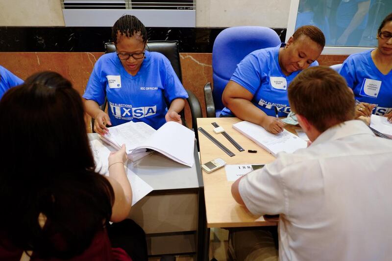International Electoral Commission employees check foreign-registered South African citizens’ names against the voters’ roll before letting them cast their vote in the country’s general election.  Antonie Robertson / The National 